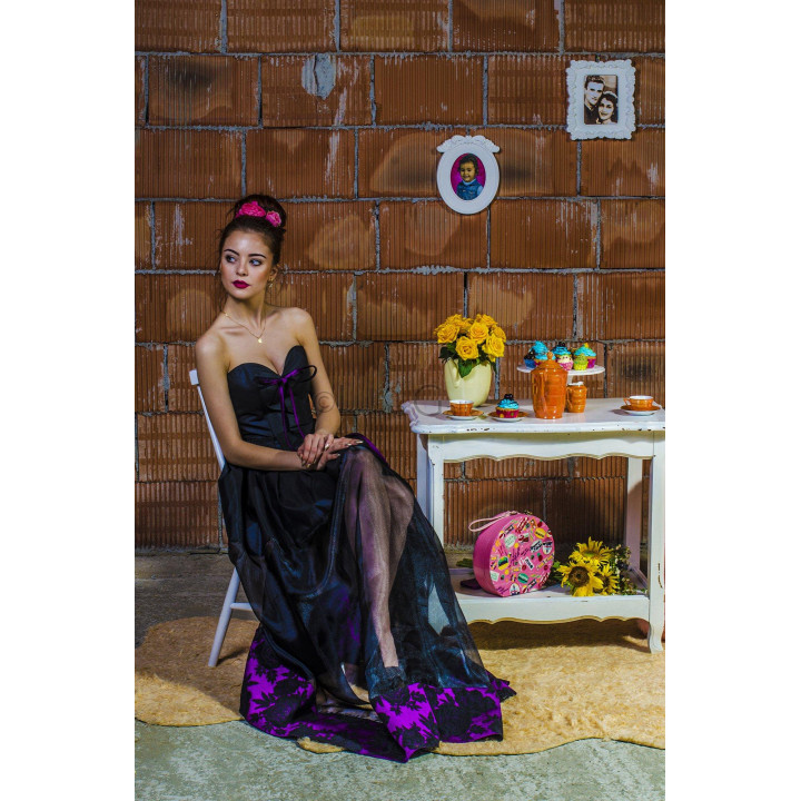 Erica 4 dress shown seated, with a sheer layer over the black skirt and purple floral hem