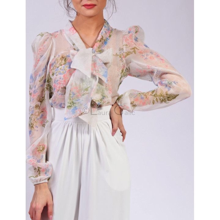 Close-up of the Lucretia blouse with pastel floral print, puff sleeves and a wide neck bow