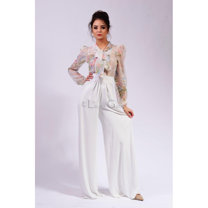 Bluză Lucretia cu imprimeu floral în nuanțe pastelate și mâneci lungi bufante, purtată cu pantaloni albi