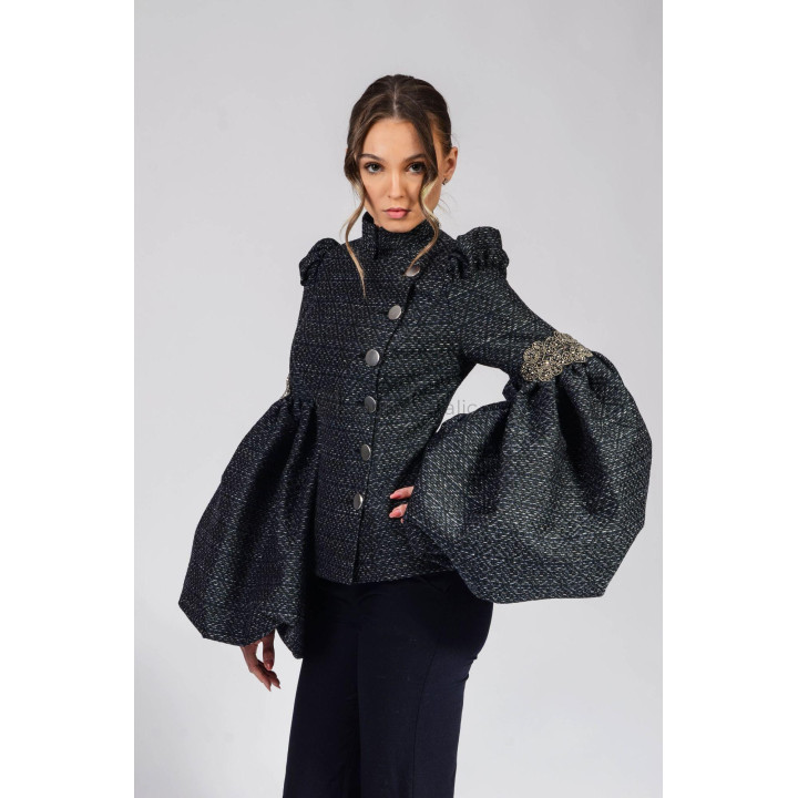 Close view of the Freia 1 jacket's oversized sleeve and gold-tone decorative appliqué