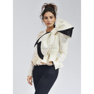 Close-up of the Carmen ivory jacket with oversized black-trimmed bow and black trousers