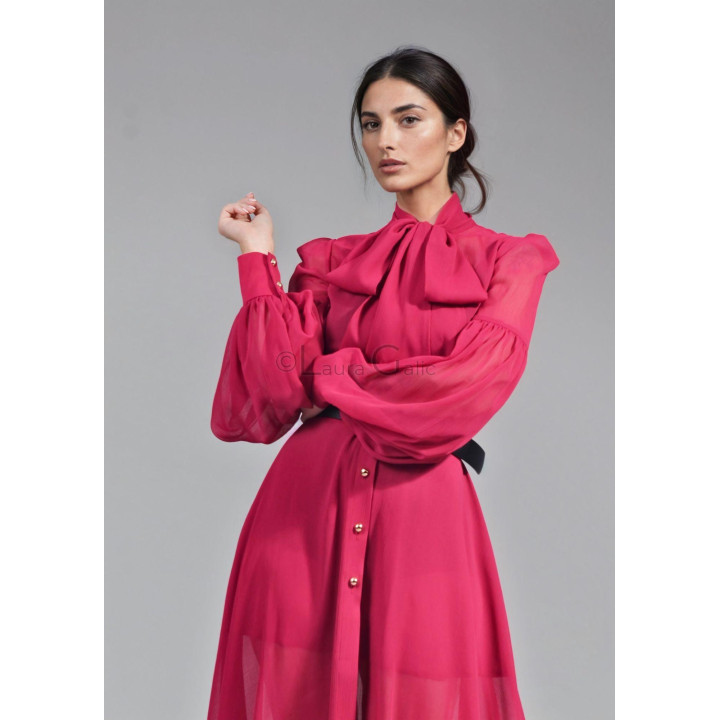 Close-up of the fuchsia Luana maxi dress, showing its oversized neck bow and voluminous sleeve with buttoned cuff