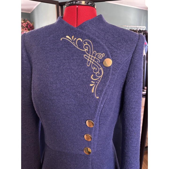 Close detail of the Tamura coat’s ornamental gold embroidery and buttons against deep blue wool